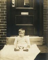 Small child sitting on a blanket on a wooden step, Philadelphia.