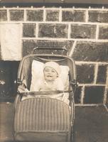 Infant in wicker carriage on sidewalk, Philadelphia.