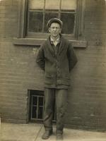 Man leaning against the brick wall of a building, Philadelphia.