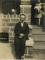 Young man seated on stone support of porch steps, Philadelphia.