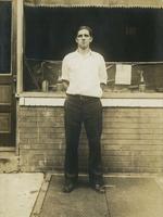 Young man standing before a storefront, Philadelphia.