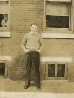 Young man in sweater standing in front of brick house, Philadelphia.
