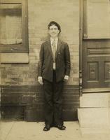 Young man in suit standing in front of brick house, Philadelphia.