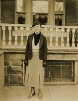 Woman standing on sidewalk in front of porch, Philadelphia.