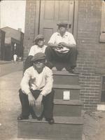 Three boys in caps sitting on wooden steps, Philadelphia.