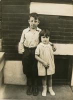 Boy and girl standing in front of brick house, Philadelphia.