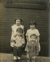 Two boys and two girls posing outside brick house, Philadelphia.