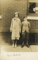 Teenage girl and younger boy standing in front of brick house, Philadelphia.