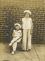 Boy and girl posing in sailor outfits in front of brick wall, Philadelphia.