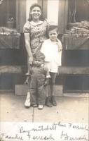 Girl and two boys standing on sidewalk in front of two windows, Philadelphia.