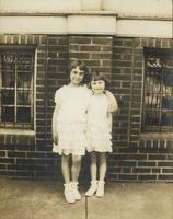 Two little girls standing in front of brick wall, Philadelphia.