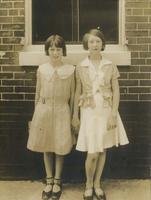 Two girls posing in summer dresses in front of brick house, Philadelphia.