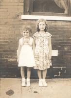 Two little girls standing in front of brick house, Philadelphia.