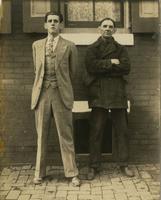 Two men, possibly father and son, standing in front of brick house, Philadelphia.