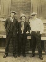 Three men standing outside a brick house, Philadelphia.