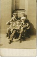 Five men, one drinking out of a flask, sitting on a doorstep, Philadelphia.