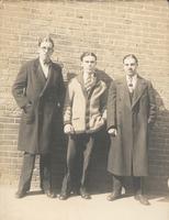 Three young men standing in front of brick wall, Philadelphia.