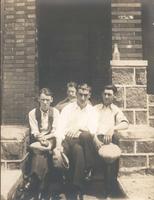 Four men sitting on stone step in front of porch, Philadelphia.