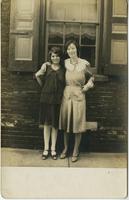 Two women standing in front of brick house, Philadelphia.