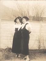 Two women standing in front of tall wooden fence, Philadelphia.