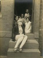 Two teenage girls and four younger children sitting at doorway of row house, Philadelphia.