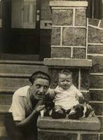 Man, baby boy, and two puppies on a stone porch, Philadelphia.