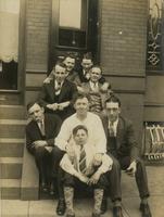 Seven men and a young boy sitting on brownstone steps, Philadelphia.