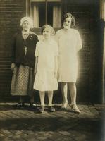 Three females standing in front of brick house, Philadelphia.