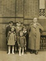 Five children and older woman standing in front of brick building, Philadelphia.