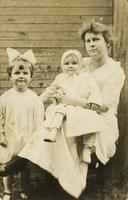 Woman with two children sitting outside a wooden house, Philadelphia.