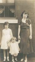 Young woman with two children standing in front of brick house, Philadelphia.