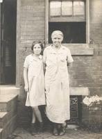 Woman and girl standing in front of house, Philadelphia.