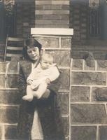 Woman with infant in front of stone porch, Philadelphia.