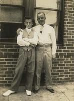Man and teenage boy standing in front of a brick house, Philadelphia.