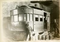 [Street-cleaning car with workers, in garage]