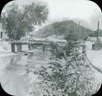[View of wooden pedestrian bridge spanning a small canal.]