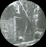 [Stone church, unidentified group sitting near ivy-covered flank.]