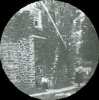 [Stone church, unidentified group sitting near ivy-covered flank.]