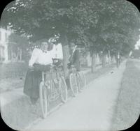 [Couple standing with bicycles, stopped on a tree-lined path, Long Island, N.Y.]