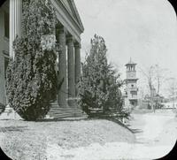 [Six columned portico of unidentified building, with clock tower in the distance.]