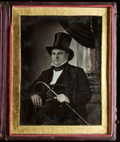 [Three quarter length, seated portrait of an unidentified man in formal clothes, wearing a top hat and holding a cane in his left hand.]