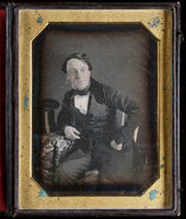[Portrait of an unidentified man, left hand on his hip, right hand resting on a table beside his top hat.]