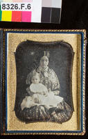 [Portrait of an unidentified young woman in a patterned dress with a child in her lap.]