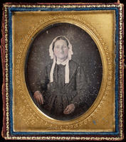 [Portrait of a sober looking, unidentified, woman wearing a checkered dress and white cap.]