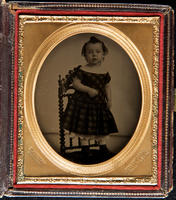 [Portrait of a little unidentified boy, with upswept hair, standing on a chair.]