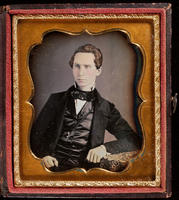 [Portrait of an unidentified young man looking to his right, wearing a big black tie and a black satin vest, with left arm is resting on a table.]