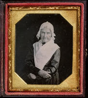 [Portrait of an unidentified, elderly woman with her arms crossed in front of her, wearing a white lace cap and a large white shawl.]