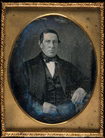 [Portrait of an unidentified man wearing a black satin vest with his left arm is resting on a book on a table.]