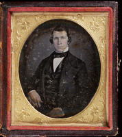 [Portrait of an unidentified, unsmiling young man, hands resting on his thighs.]