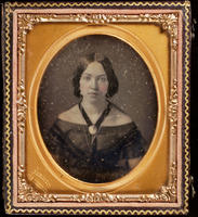 [Portrait of an unidentified young woman, hair parted in the middle, wearing a black ribbon attached to a pin at her neck.]